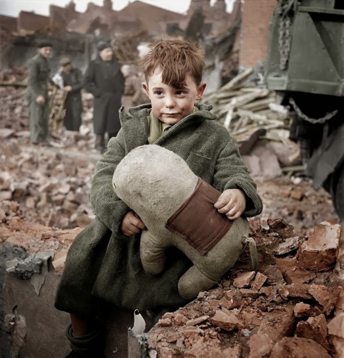 Abandoned boy holding a stuffed toy animal amid ruins following German aerial bombing of London, 1940 color