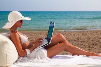 woman on beach working on  laptop against the sea