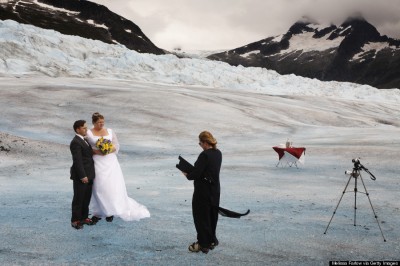 Diane Pearson performs the wedding on the Mendenhall Glacier in the Tongass National Forest. A couple who met on the internet decided to be married in this unusual way. Diane Pearson of Pearson's Pond Spa and Inn arranges weddings and the tourists are transported by helicopter onto the glacier. Anna Hall and John Bohach from California, strapped on crampons with their formal attire and were married on the first sunny day in Juneau in three weeks. A video camera records the ceremony. The cake and champagne sit on the table for the celebration.