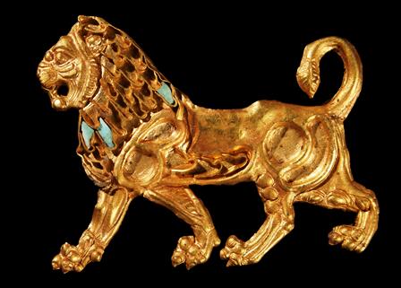 Χρυσό έλασμα σε μορφή λιονταριού, αρχικά ραμμένο σε ύφασμα. Πιθανώς ήλθε ως λάφυρο από την Περσία και αφιερώθηκε στους Μεγάλους Θεούς από κάποιον στρατιώτη του Μεγάλου Αλεξάνδρου μετά την επιστροφή του από την εκστρατεία. 4ος αι. π.Χ. 