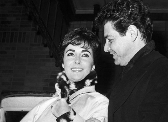 British actress Elizabeth Taylor is helped by her husband American singer Eddie Fisher, as she leaves Presbyterian hospital in New York, United States on Dec. 13, 1959, following a bout with double pneumonia. She rode from her room in a wheelchair but walked out with her husbands help. They went to their suite in the Waldorf-Astoria Hotel. The actress entered the hospital on Nov. 26, 1959. (AP Photo)