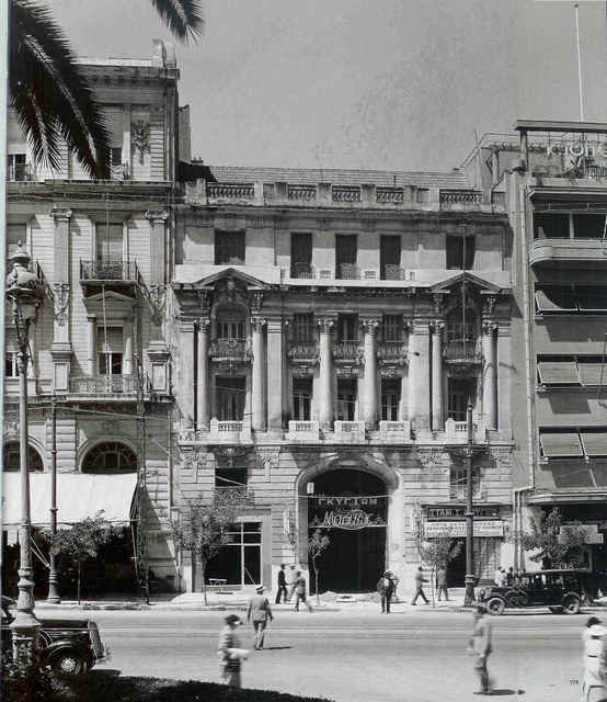"Η πρώτη εκδοχή του κτηρίου Νικολούδη στην οδό Πανεπιστημίου, [σημ. όπως απεικόζεται στην φωτογραφία] για την οποία δεν υπάρχουν πλήρη στοιχεία, σχεδιάσθηκε το 1897 από τον ίδιο τον αρχιτέκτονα Αλέξανδρο Νικολούδη, σπουδαστή ακόμα της Ecole des Beaux-Arts στο Παρίσι. 