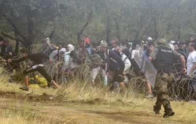epa04892970 Migrants who wait more then 48 hours on the Greek side of the border line, jump over razer wire to cross in Macedonia near southern city of Gevgelija, The Former Yugoslav Republic of Macedonia, 21 August 2015.Macedonian special police forces arrived yesterday morning and blocked the illegal border crossing between Macedonia and Greece. They don't give permission to the migrants to pass in Macedonia. Macedonian government has declared emergency situation in the south and north border with Greece and Serbia due to rising number of migrants and fugitives from Syria, Afganistan, Iraq, Pakistan and Somalia. From the beginning of the year to mid-June 2015, nearly 160,000 migrants landed in the southern European countries, mainly Greece and Italy, on their way to wealthier countries in Western and Northern Europe, according to estimates by the International Organization for Migration (IOM). EPA/GEORGI LICOVSKI