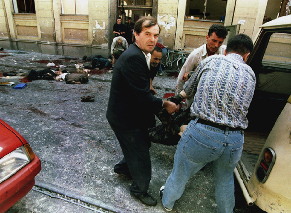 Dead and wounded are loaded into cars outside of the city indoor market after a mortar shell exploded at the entr anceto the building August 28. An artillery shell hit Sarajevo's crowded main street street on Monday, killing at least 32 people and wounding another 40 residents